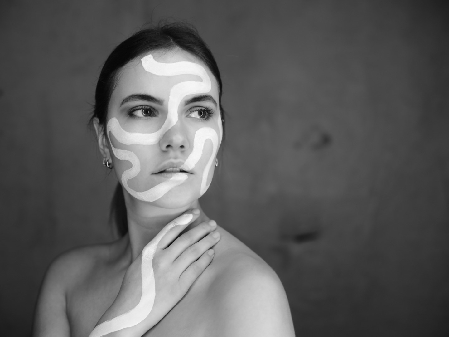 black and white portrait of a young woman with white body paint in her face